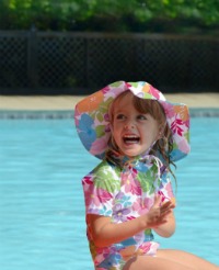 Little girl wearing iPlay cloth swim diaper and iPlay sun hat